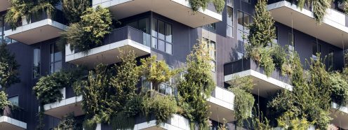 A corner of a modern multi-storey building with panoramic windows and extensive greenery on balconies | Pipelife