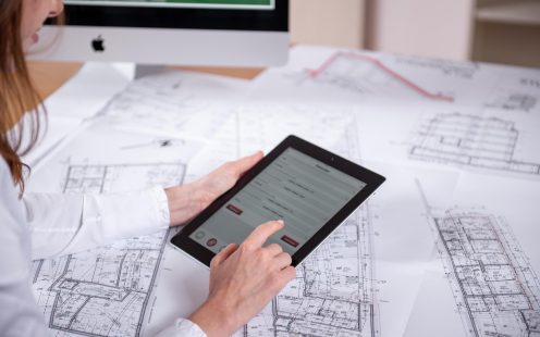 Woman at workplace with blueprint holding tablet computer