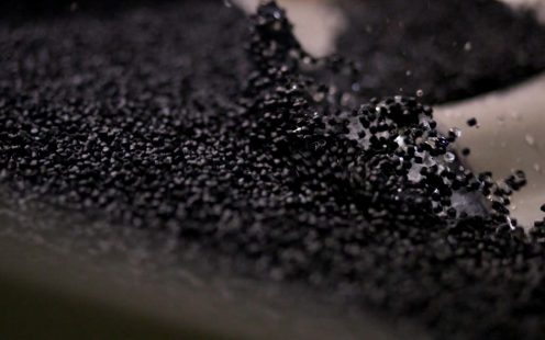 A close-up of black PE pellets produced from recycled plastic waste.